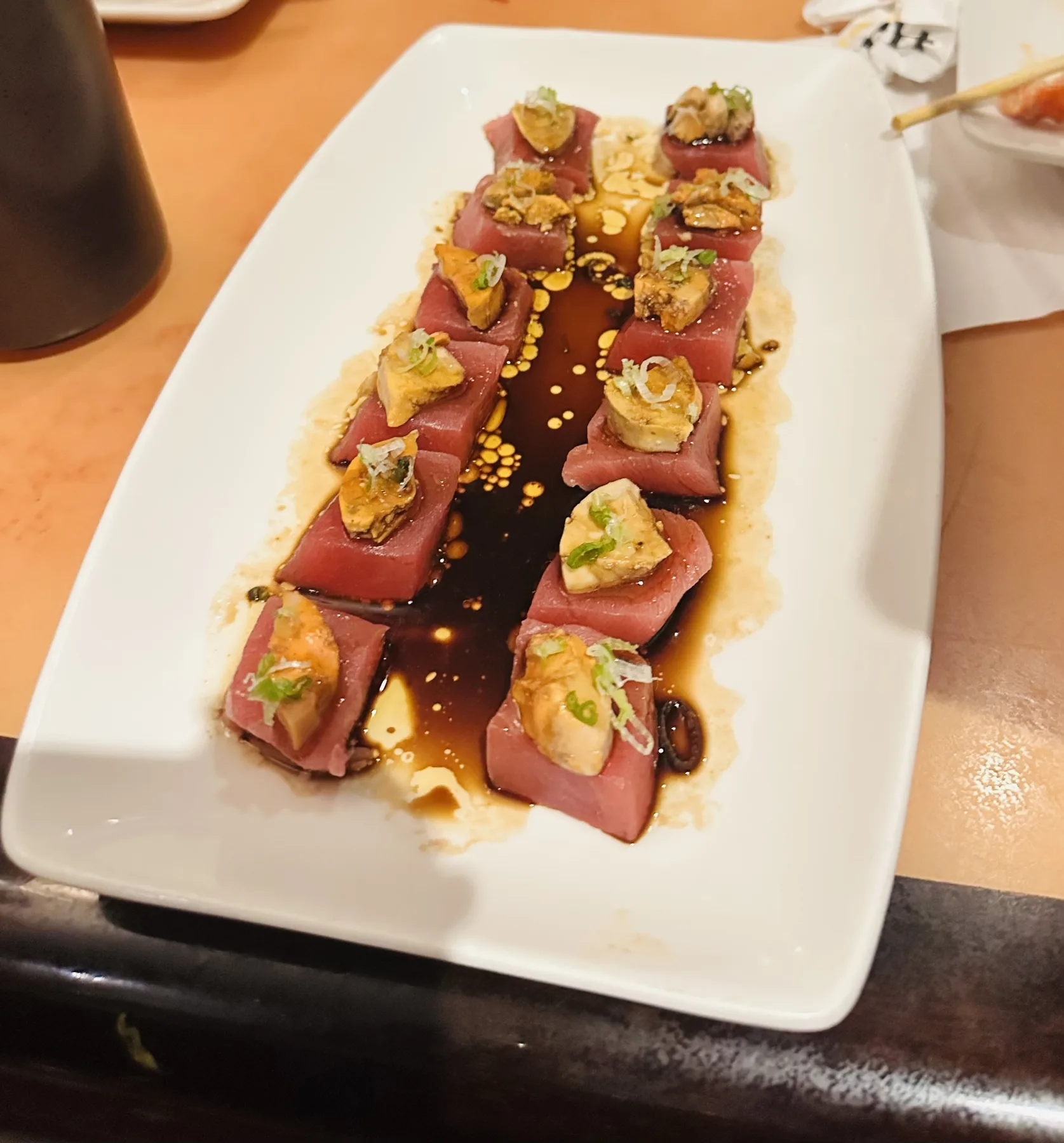 Seared tuna appetizer topped with uni, scallions, and a glossy brown sauce