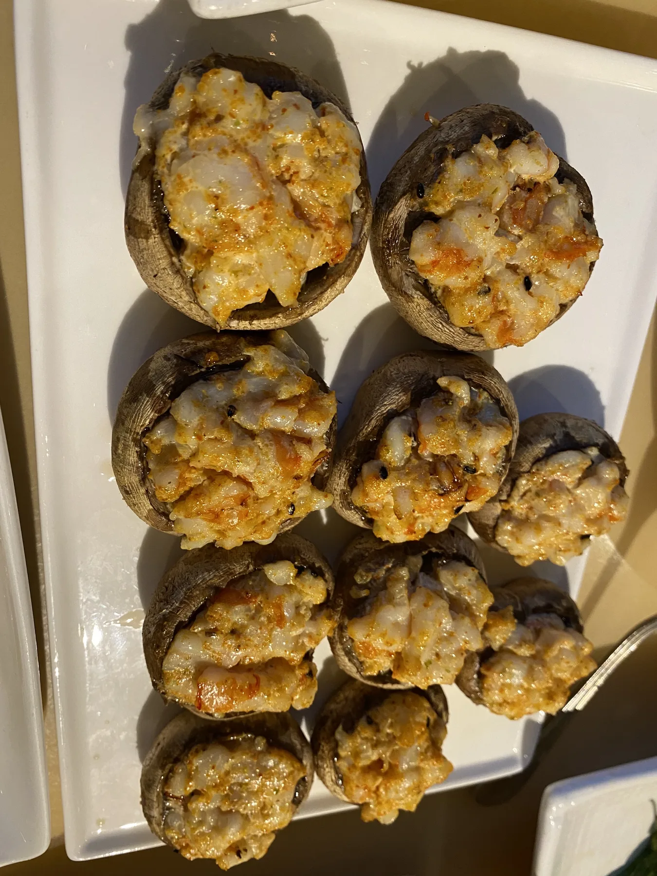 Stuffed mushroom caps with a golden breadcrumb topping, arranged on a white plate
