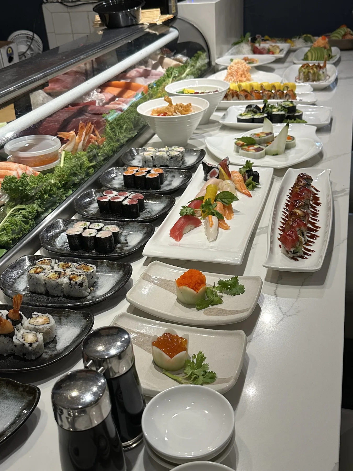 Sushi bar counter at Hanami Restaurant with fresh nigiri, sashimi, and specialty rolls on display