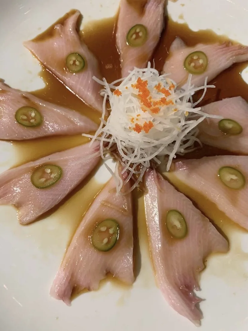 Hamachi sashimi slices topped with jalapeño rings, served with tobiko and ponzu sauce